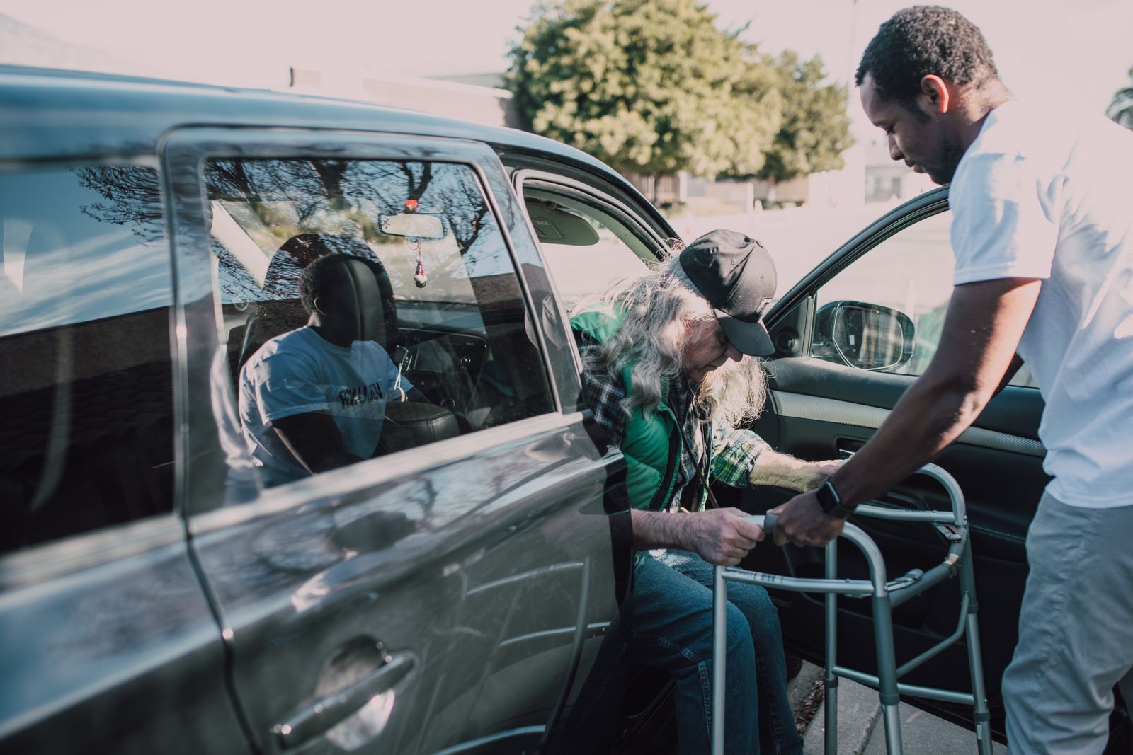 Family members helping an older parent out of a car